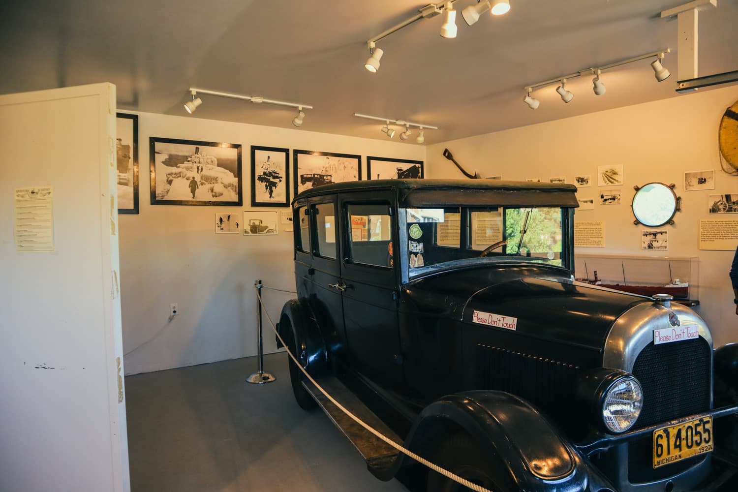 A vintage automobile and historic photographs on display inside one of Eagle Harbor Lighthouse's museum buildings