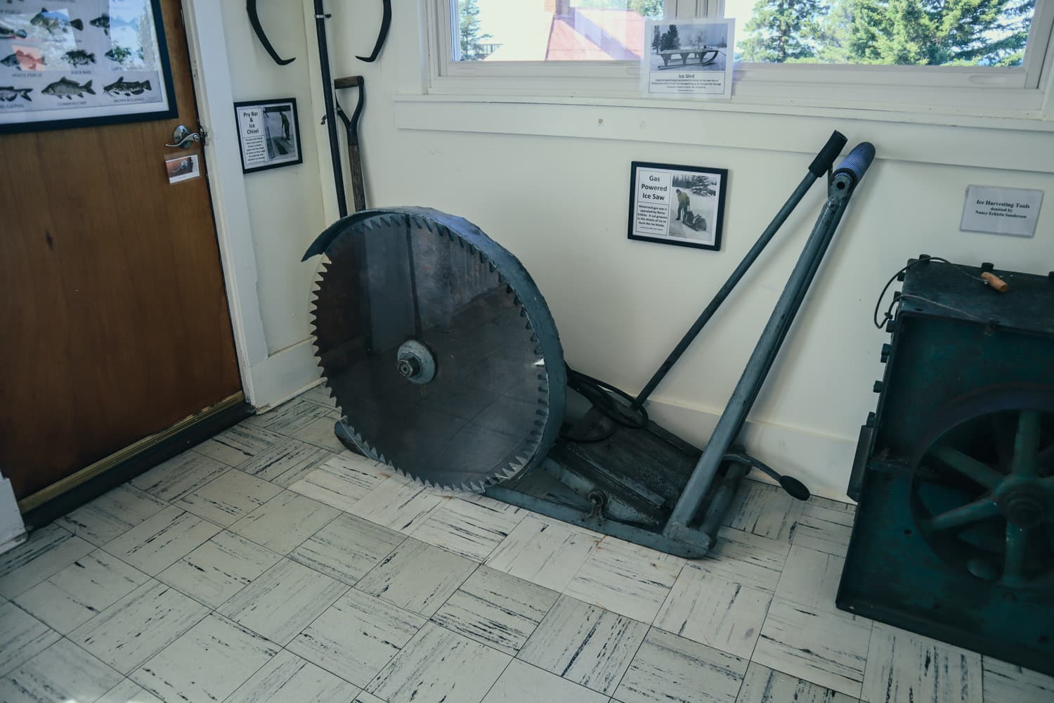 A giant antique saw blade and old tools on display inside an Eagle Harbor Lighthouse museum building