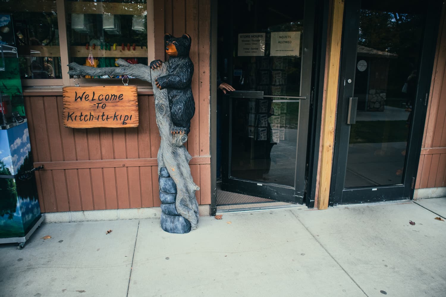 A carved bear and Welcome to Kitch-iti-kipi sign outside the park store at Palms Book State Park