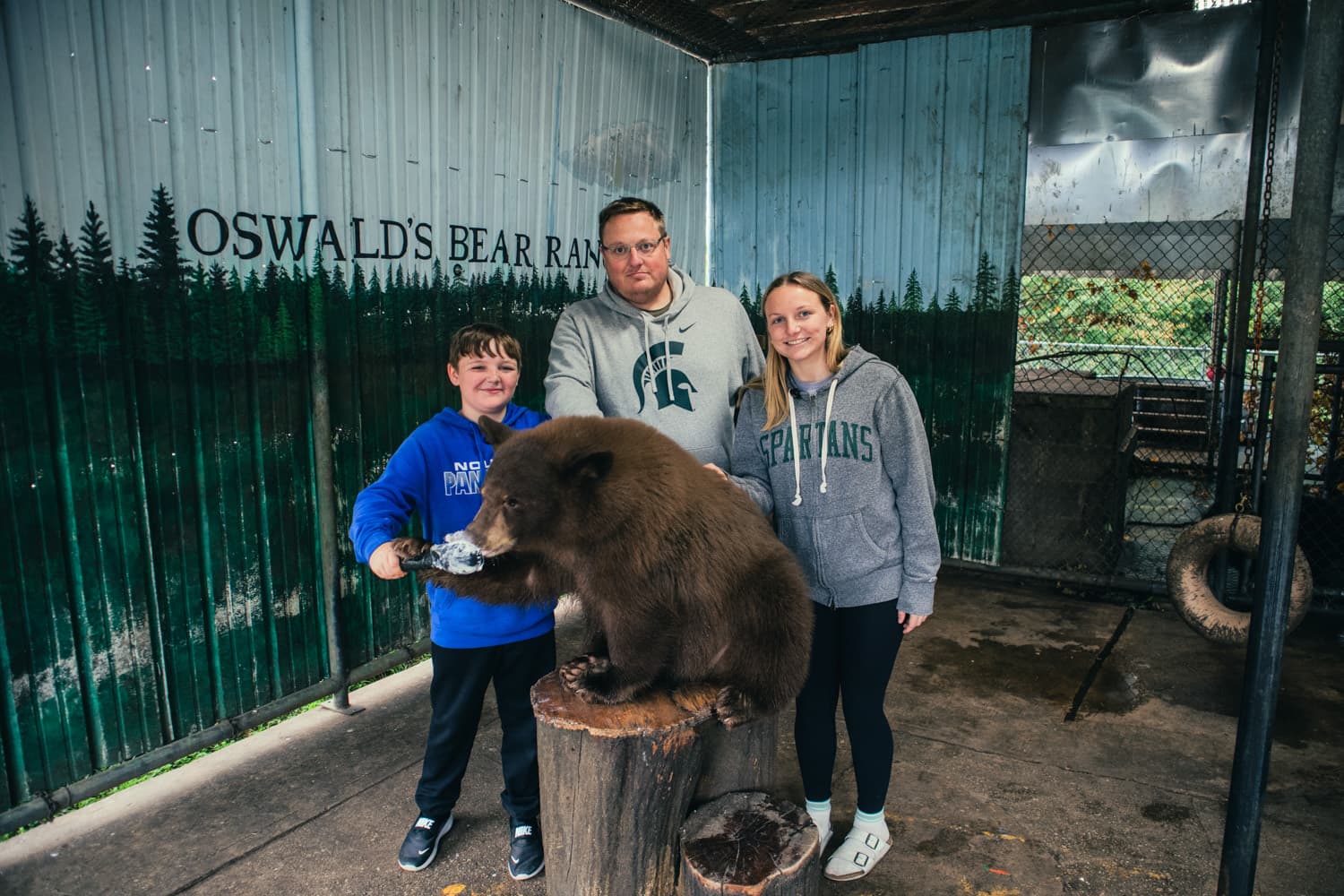 Mike with his son Atticus and daughter Hallie posing with a bear cub at Oswald's Bear Ranch