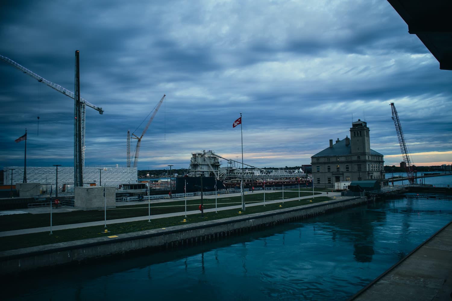 Construction cranes over the new lock project at the Soo Locks under a dramatic evening sky