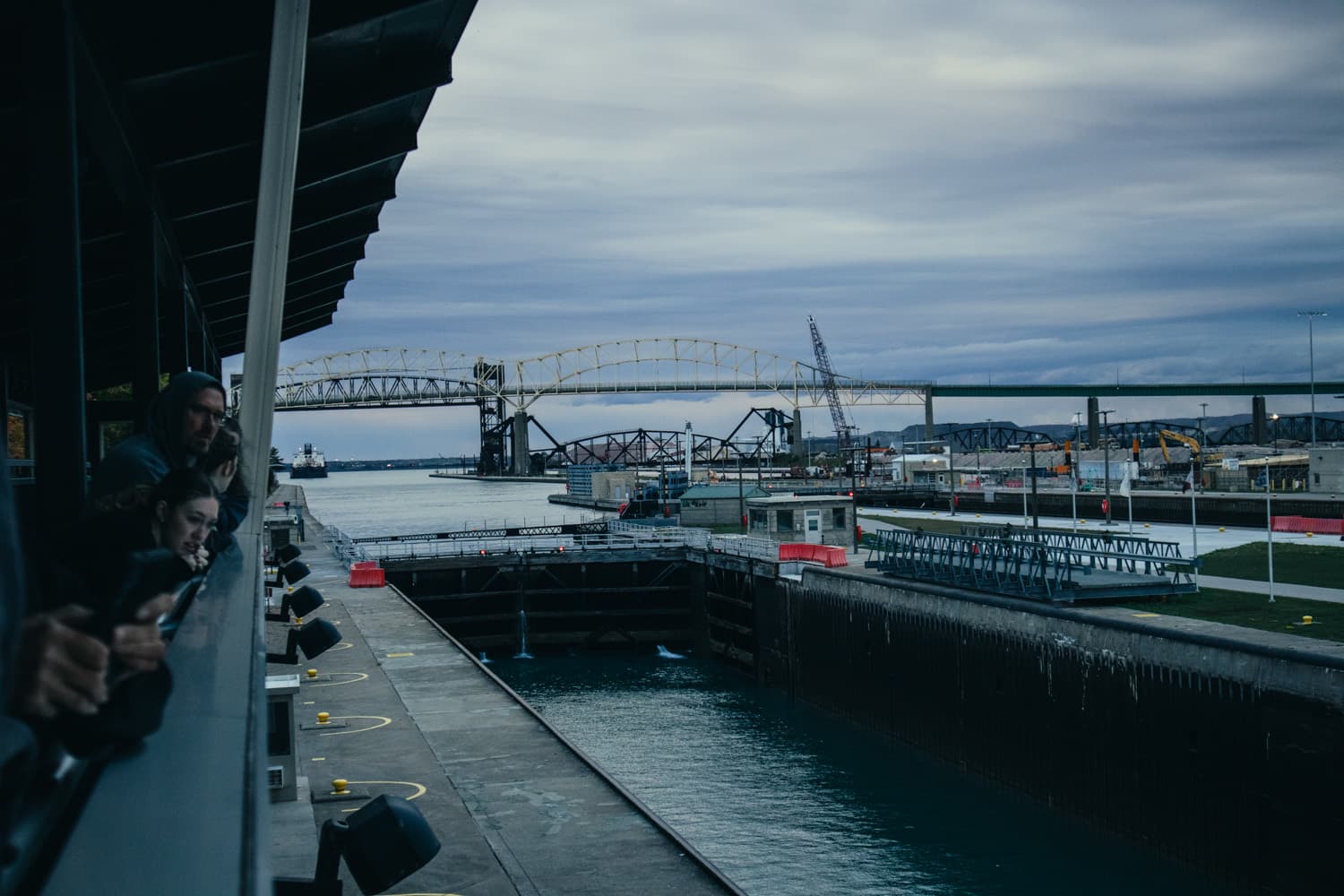 Visitors on the Soo Locks observation platform looking toward a lock and the International Bridge to Canada