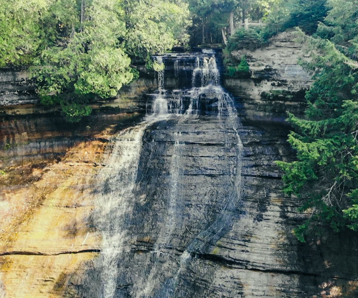 Full view of Laughing Whitefish Falls from the top observation platform, showing the entire cascade and the viewing deck above